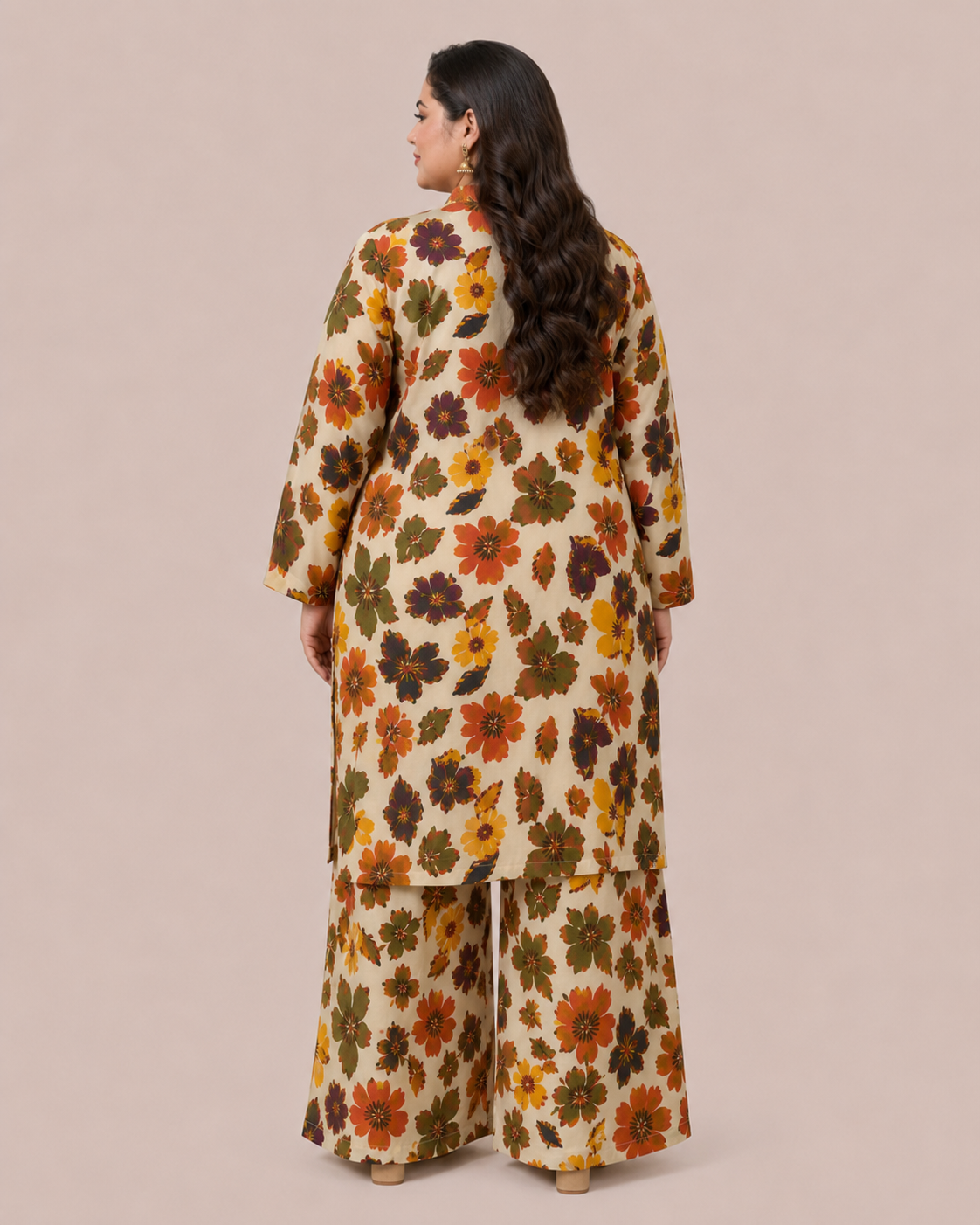 A woman shown from the back wearing a cream-colored two-piece kurta set with a dense, colorful floral pattern in orange, yellow, green, and brown, set against a solid beige studio background.