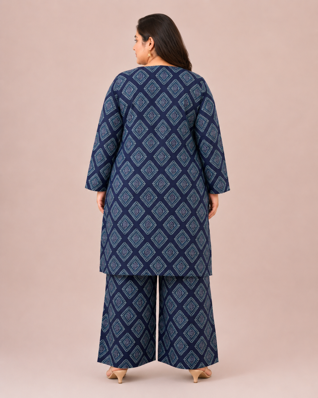 Front three-quarter view of a plus-size model posing in a matching navy blue and cream geometric grid block printed cotton lawn kurta and wide trouser co-ord set.