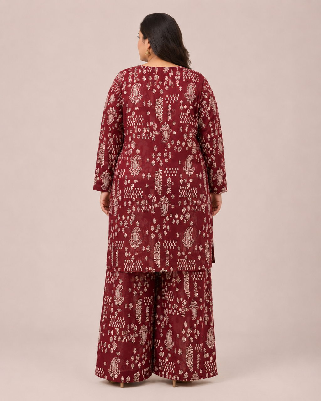 A woman viewed from the back wearing a matching three-piece traditional outfit with a deep maroon base and off-white block-print patterns, set against a plain beige studio background.