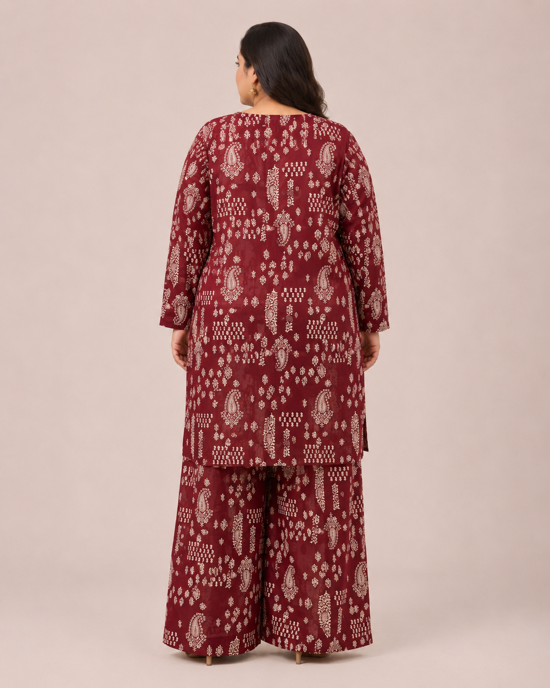 A woman viewed from the back wearing a matching three-piece traditional outfit with a deep maroon base and off-white block-print patterns, set against a plain beige studio background.