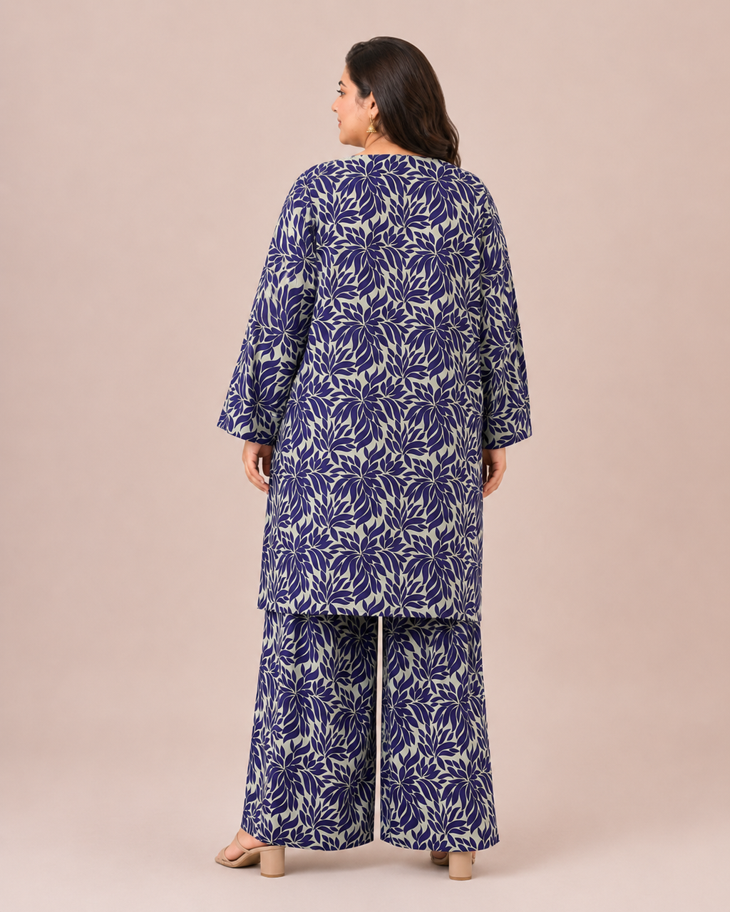 Back view of a plus-size model posing in a matching indigo blue and steel gray abstract leaf printed cotton lawn kurta and wide trouser co-ord set.