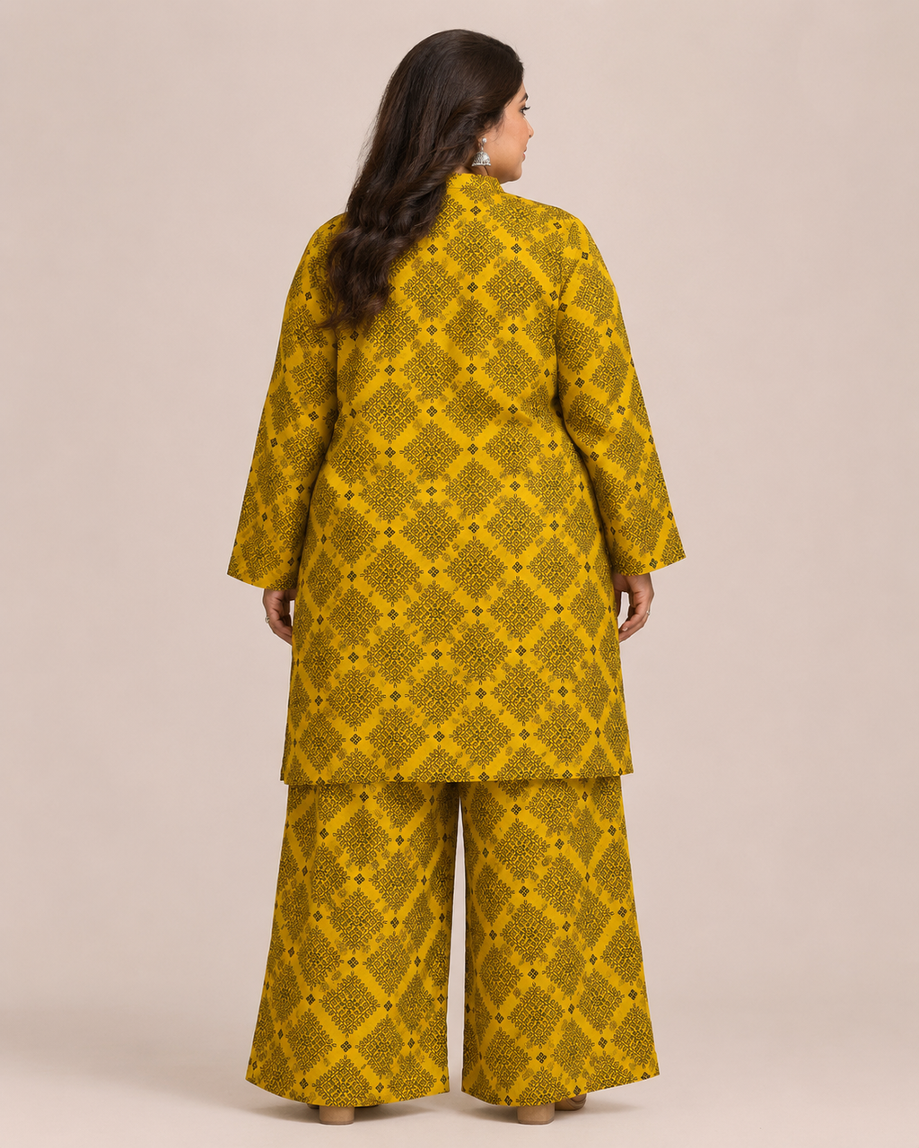 Front view of a smiling plus-size model posing in a matching mustard yellow and black geometric checkered printed cotton lawn kurta and wide trouser co-ord set.