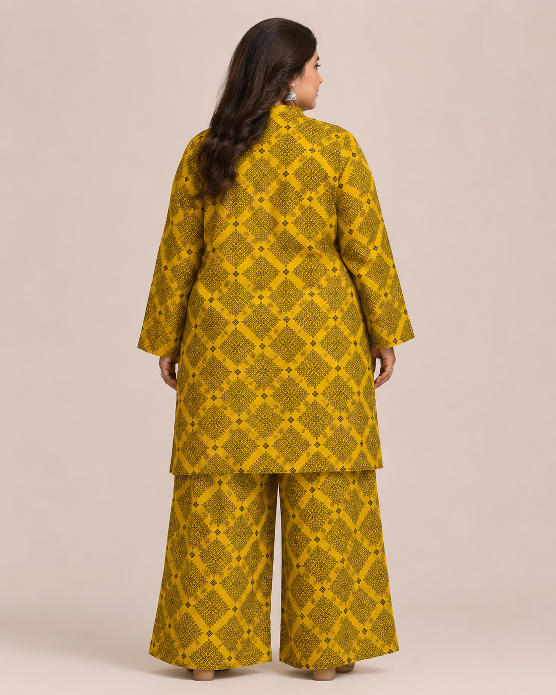 Front view of a smiling plus-size model posing in a matching mustard yellow and black geometric checkered printed cotton lawn kurta and wide trouser co-ord set.