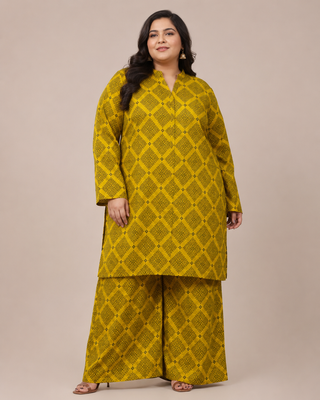A woman modeling a mustard yellow two-piece kurta and trouser set with a matching geometric block print, set against a solid beige studio background.