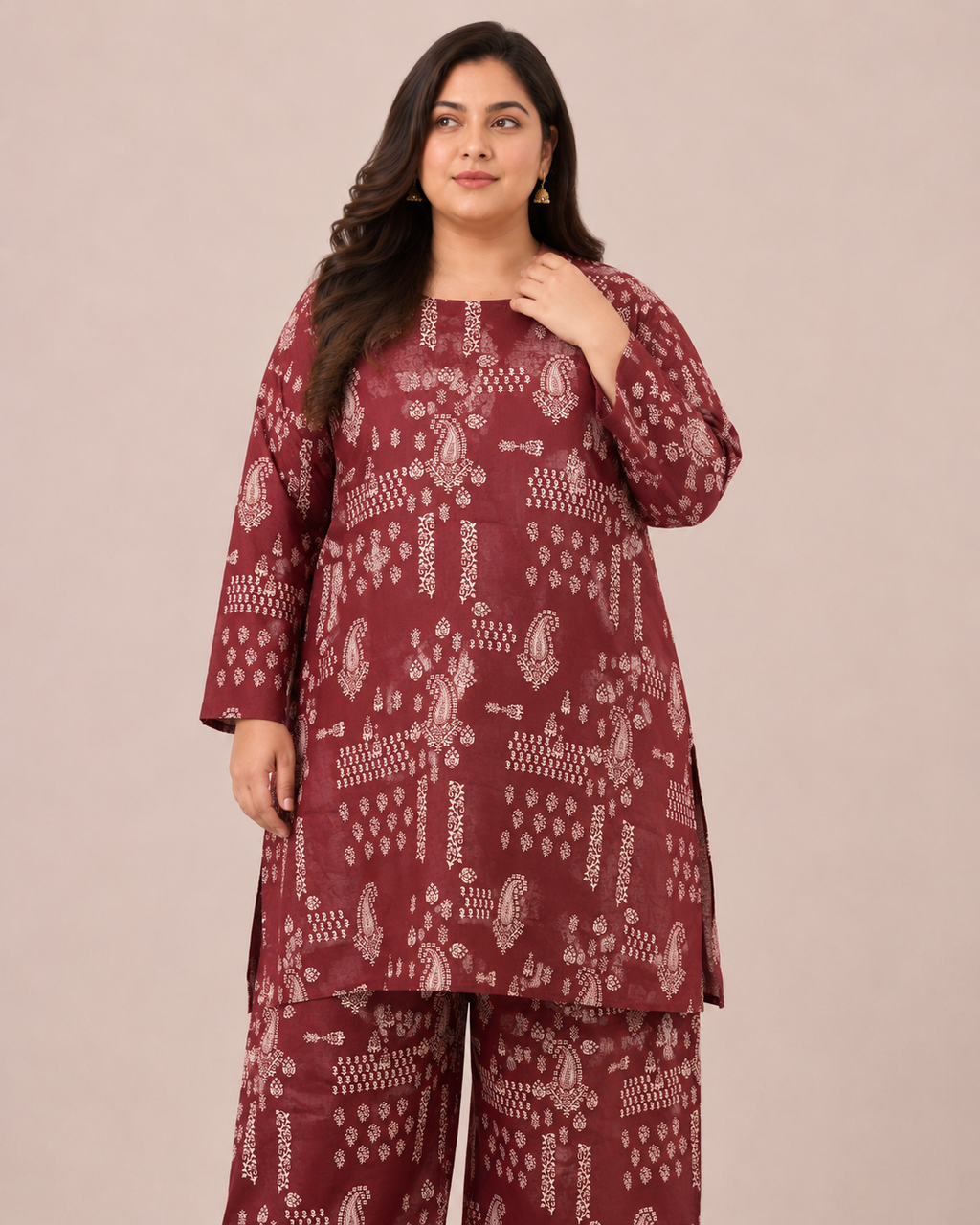 A woman modeling a three-piece maroon kurta set with white block-print patterns, consisting of a long-sleeve tunic, matching pants, and a dupatta, set against a plain beige studio background.