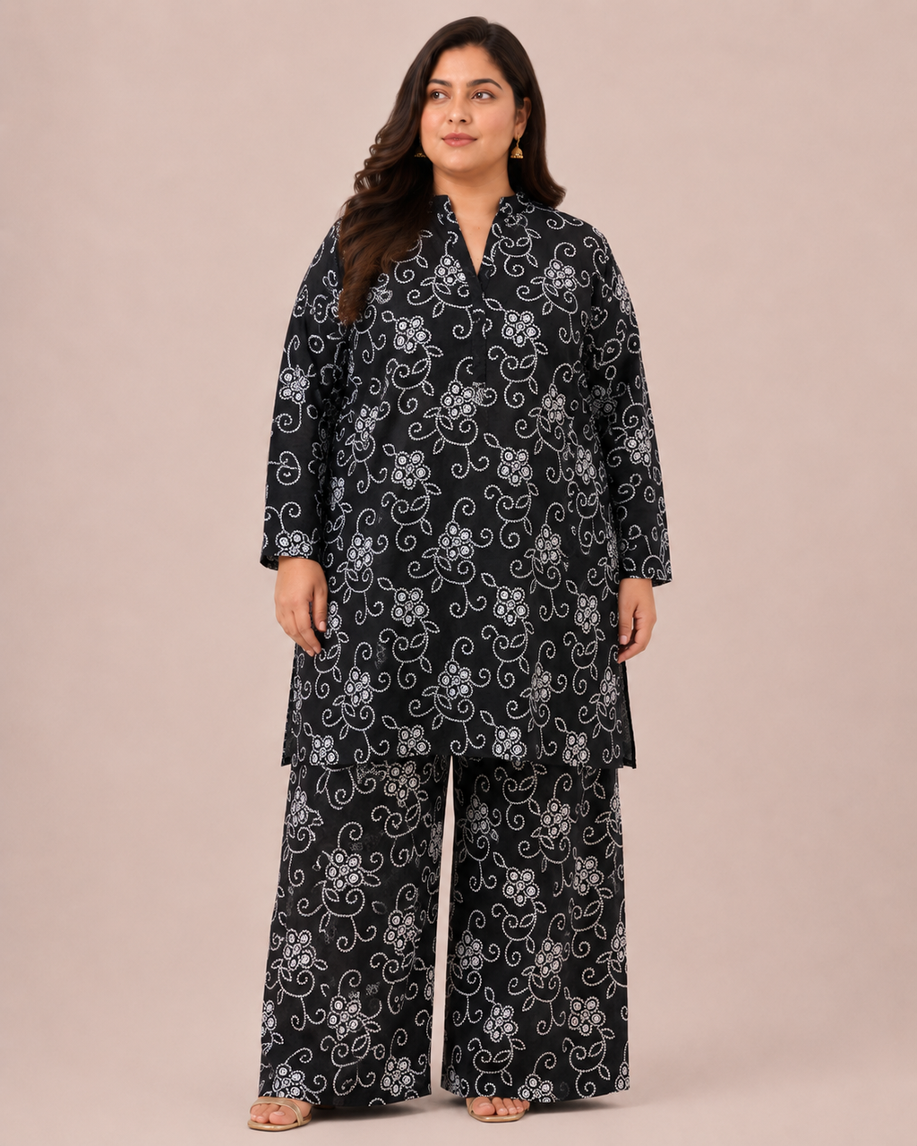 Front view of a smiling plus-size model posing in a matching black and white floral vine printed cotton lawn kurta and wide trouser co-ord set.