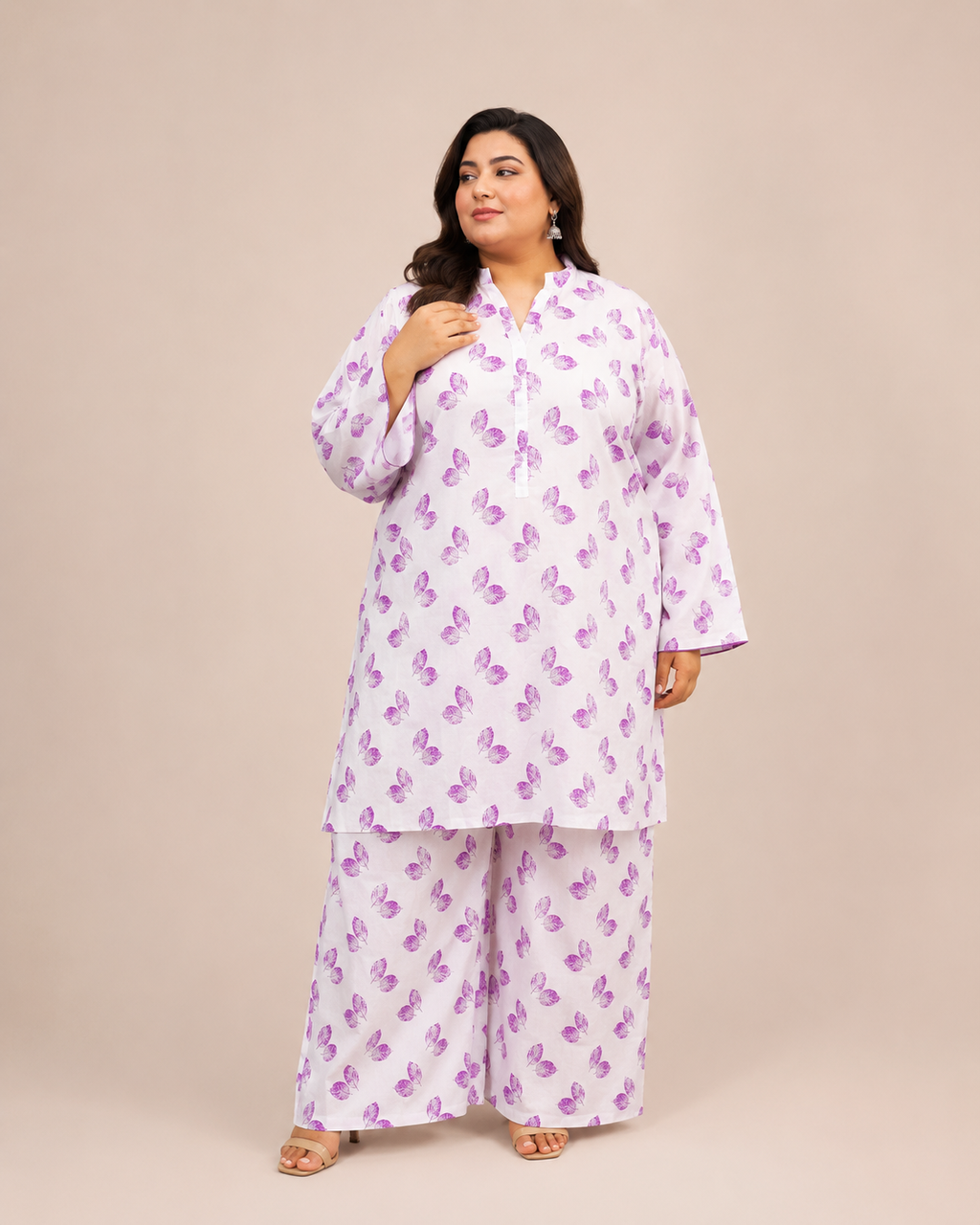Front view of a smiling plus-size model posing in a matching white and lavender leaf printed cotton lawn kurta and wide trouser co-ord set.