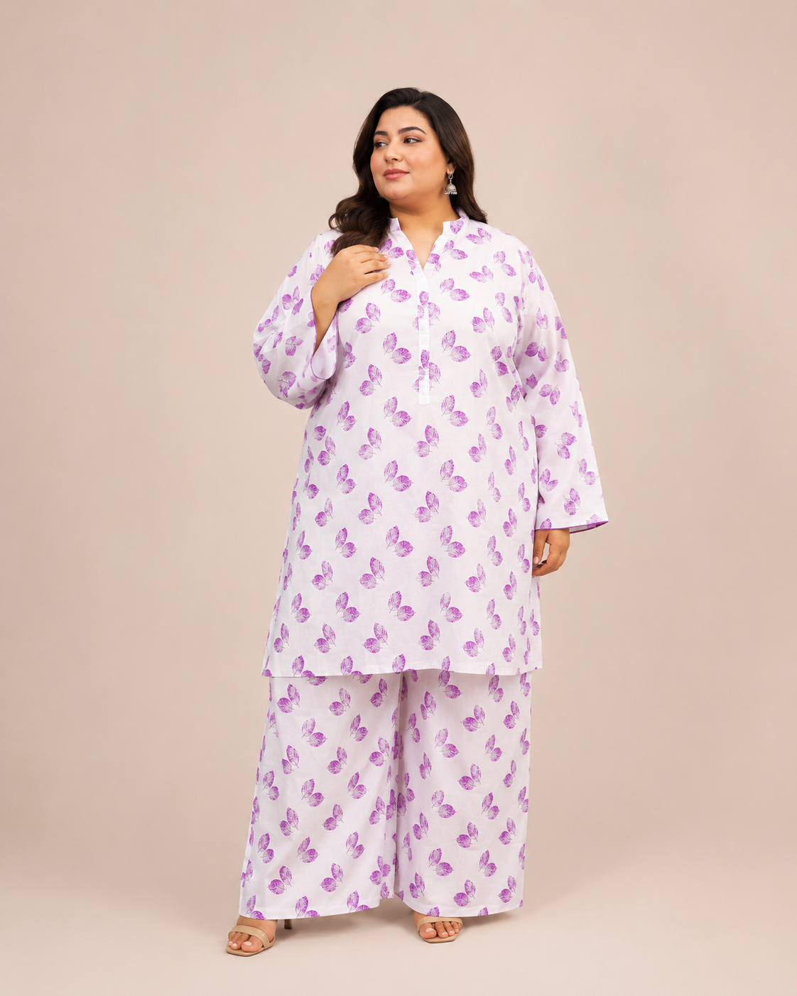 Front view of a smiling plus-size model posing in a matching white and lavender leaf printed cotton lawn kurta and wide trouser co-ord set.